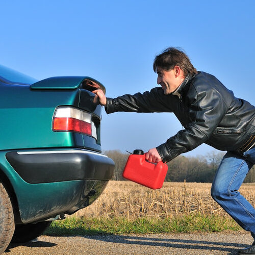 Man holding a gas can and pushing a car.